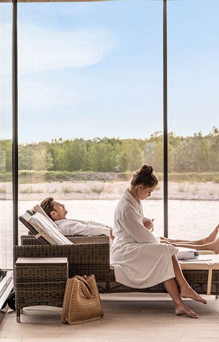 Couple lying in the St. Martins Lodge Lake treatments sunbathing area and woman leafing through a magazine